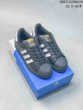 Pair of black and white adidas Superstar sneakers displayed on a blue shoebox, showing the shell toes and side stripes.