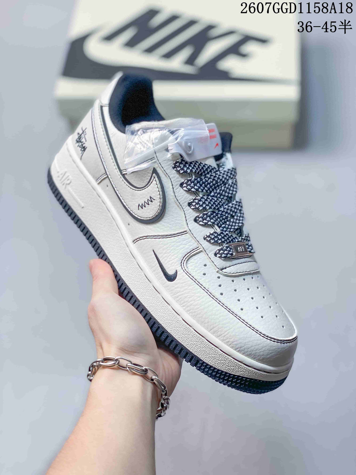 Close-up of a white low-top sneaker showing layered side panels, a dark swoosh, patterned laces, perforations, and Air branding.
