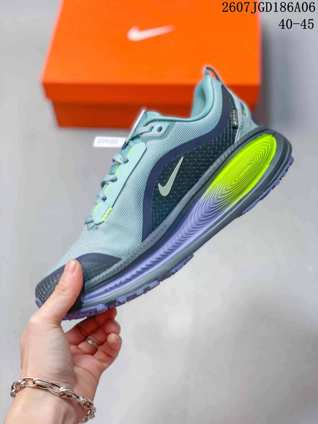 Side profile of the gray sneaker showing the layered textile-style upper, Nike Swoosh, neon yellow midsole insert, and purple outsole.
