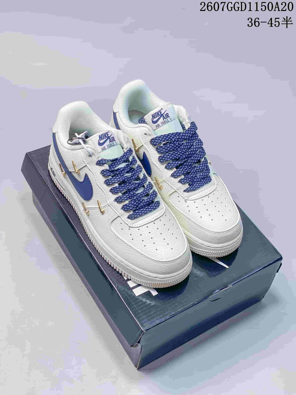 Pair of white Nike low-top sneakers with blue Swoosh branding, blue laces, and gold decorative Swoosh details.