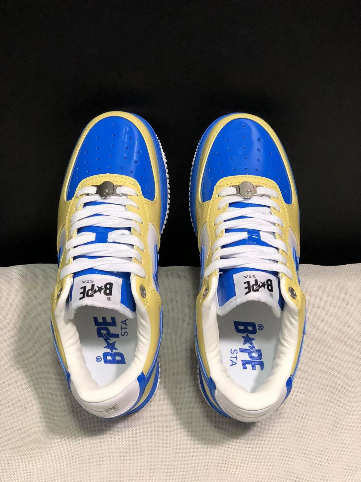 Top view of blue and yellow BAPE STA sneakers with white laces and perforated toe panels