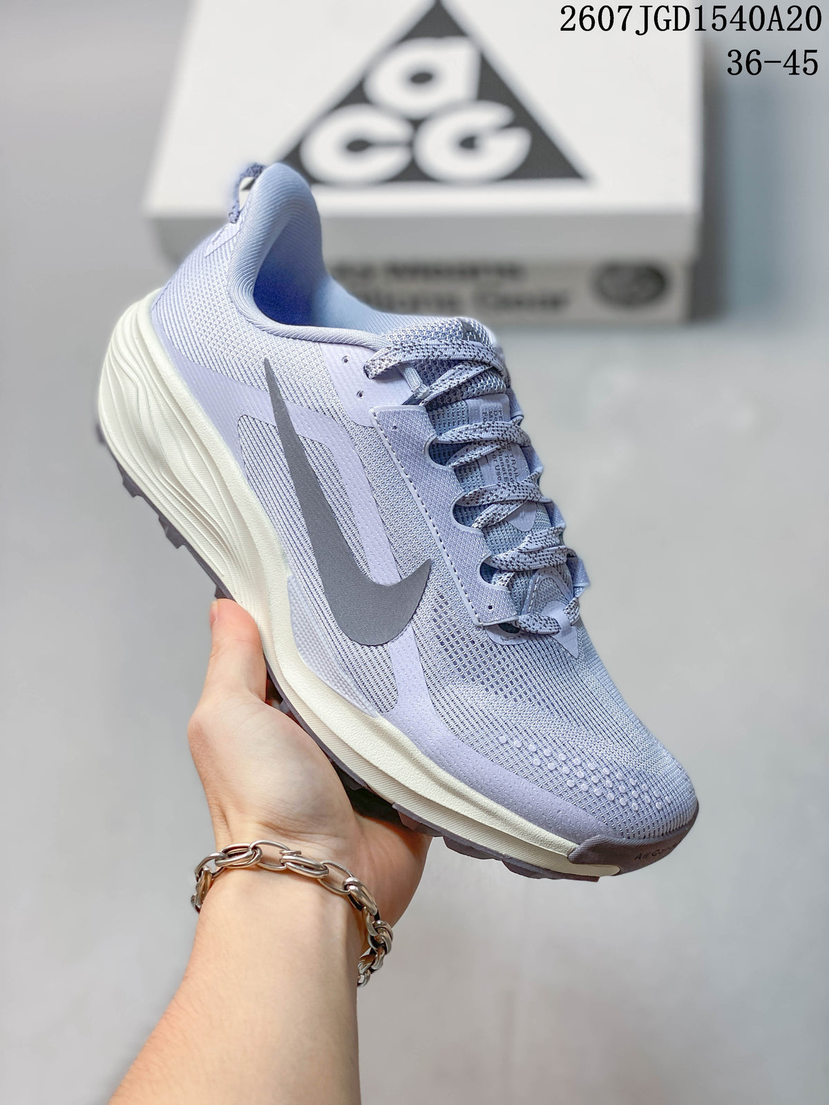 Angled side view of the light lavender Nike ACG Pegasus Trail sneaker showing the textured upper, gray Swoosh, lace system, cushioned midsole, and lugged outsole.
