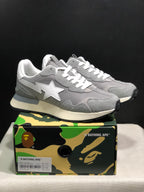 Pair of grey BAPE ROAD STA EXPRESS sneakers displayed on a camouflage BAPE shoebox; the box label shows EU 42 and Grey.