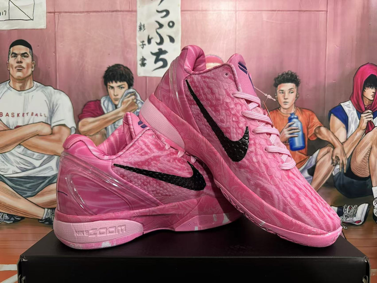 Angled display of two pink basketball sneakers showing the black swooshes, high-top collars, textured uppers, and pink soles.