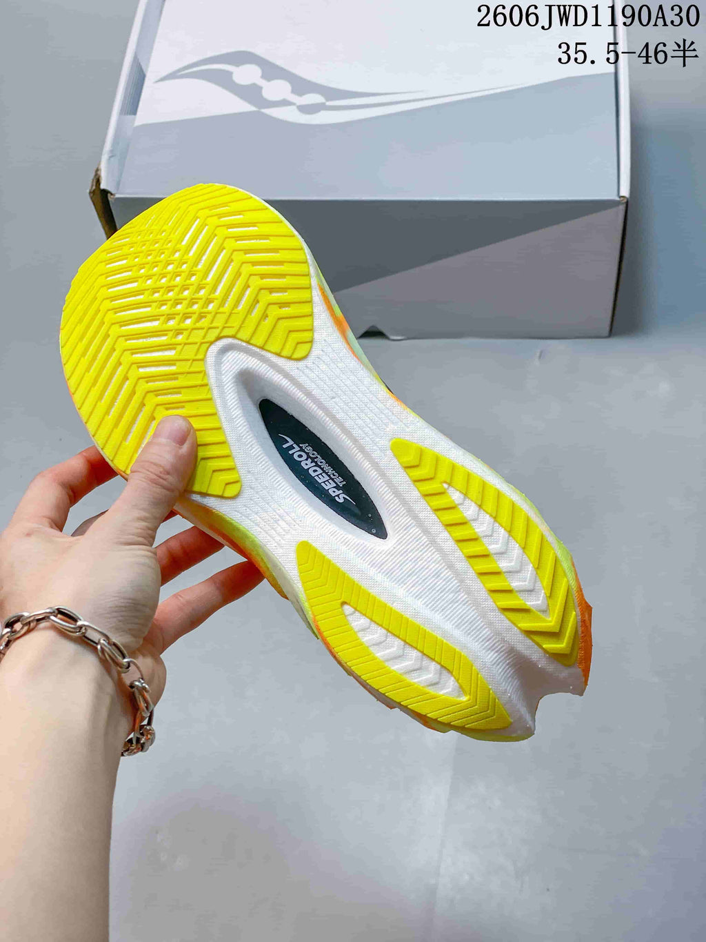 Underside of a Saucony Endorphin Pro shoe showing a white sole with bright yellow traction sections.