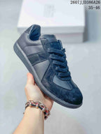 Angled side view of the black low-top sneaker showing the lace-up construction, layered side panels, padded collar, and textured outsole.