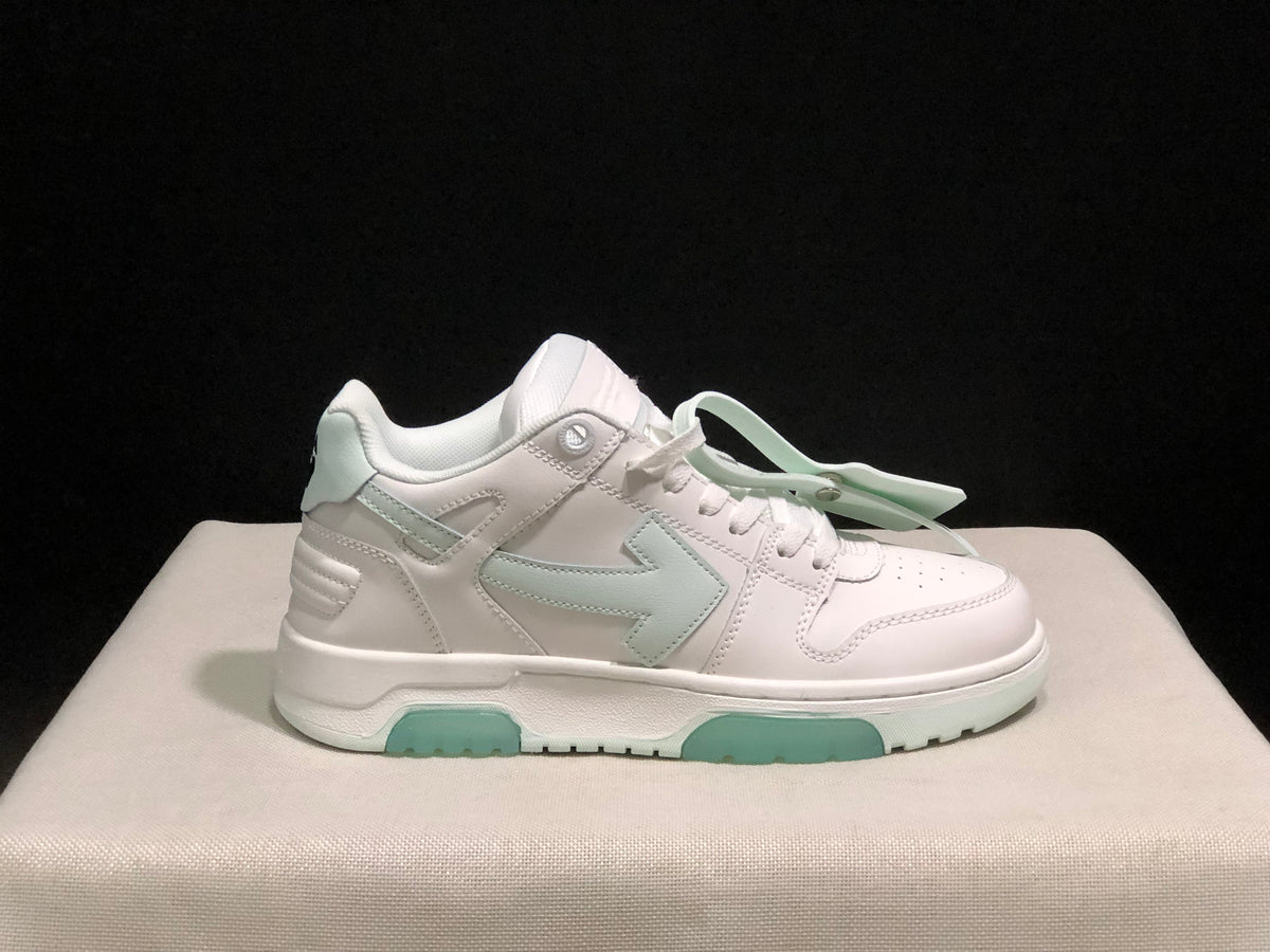 Close side profile of a white low-top sneaker with pale mint side branding accents and outsole inserts.