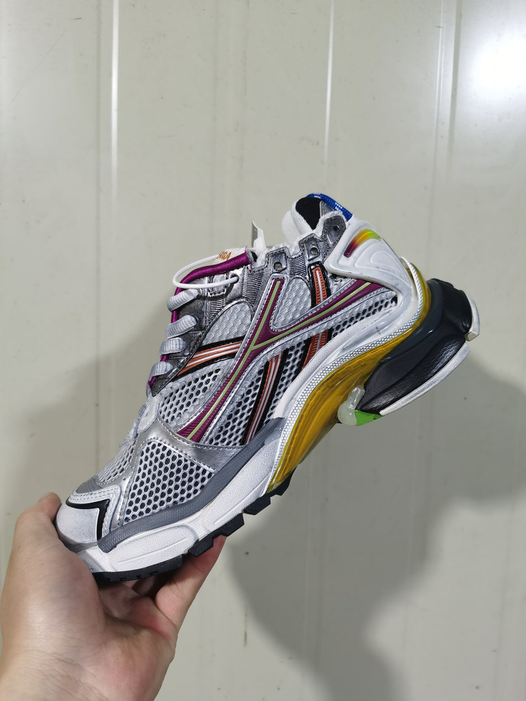 Angled view of the sneaker's opposite side, showing the metallic upper, mesh-style panels, contrasting overlays, laces, and multicolor outsole.
