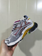 Angled view of the sneaker's opposite side, showing the metallic upper, mesh-style panels, contrasting overlays, laces, and multicolor outsole.