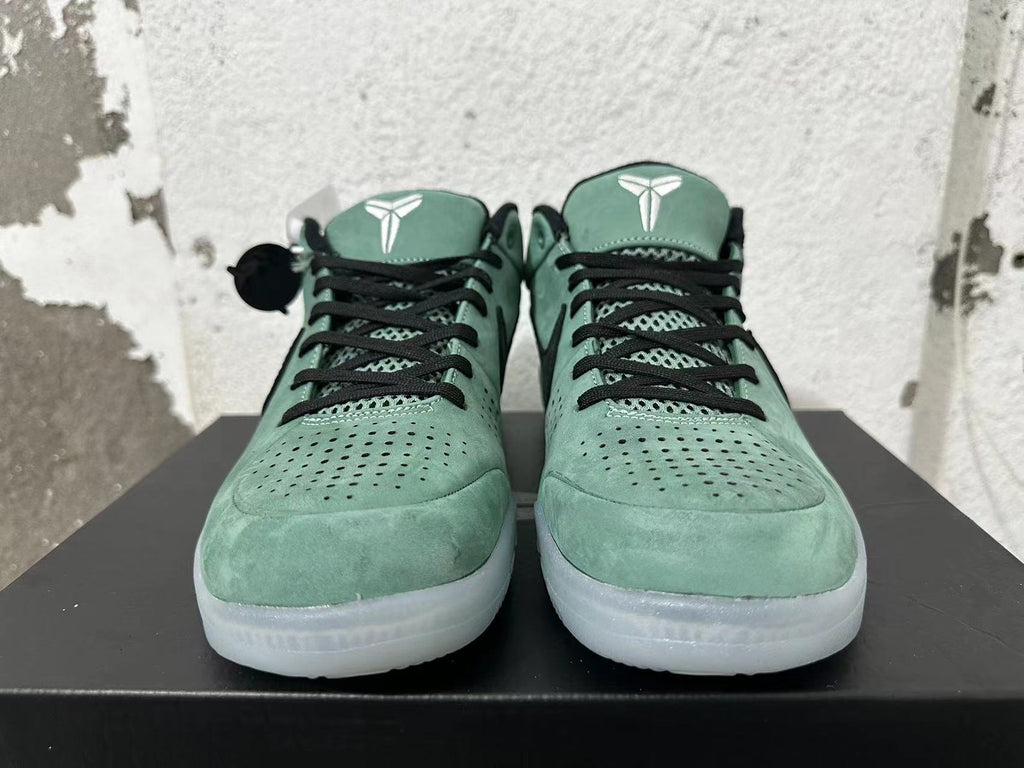 Front view of green Nike Kobe basketball shoes with black laces and perforated toe panels.