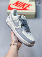 Close side view of a white and gray sneaker showing the gray overlays, patterned side panel, perforated toe box, and textured gray outsole.