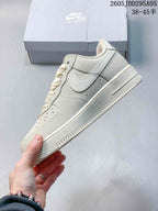 Side view of a cream low-top sneaker showing the tonal Swoosh, stitching, midsole, and outsole.