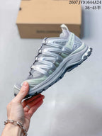 Side profile showing the gray and pale green upper, structured panels and rugged outsole.