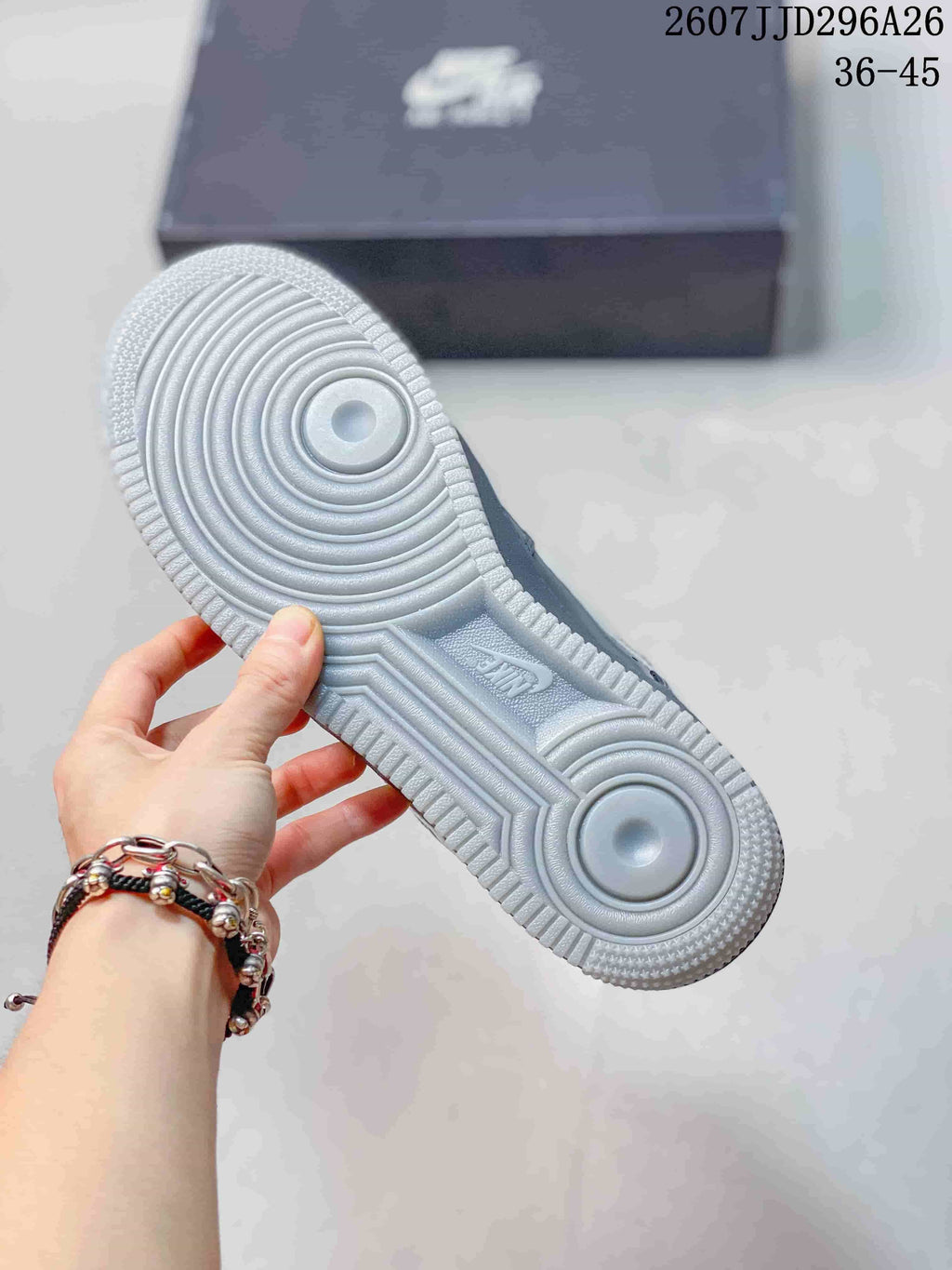 Underside view of a grey sneaker showing the circular rubber outsole pattern and central Nike detail; image text shows 2607JJD296A26 and 36–45.