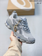 Angled side view of the gray sneaker showing the mesh upper, layered panels, outsole, and decorative side charm.
