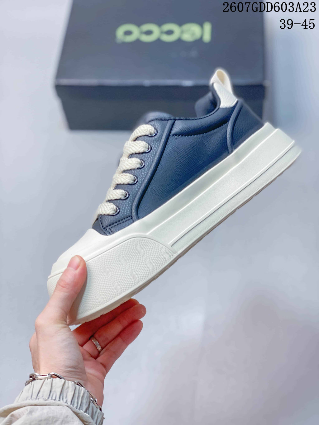 Side view of the navy sneaker with cream laces, white platform-style sole, and textured side panel.