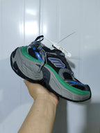 Close angled view of the black-and-green chunky sneaker, showing mesh panels, layered overlays, and the sculpted outsole.