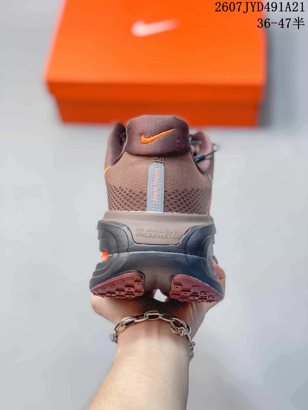 Rear view of the brown sneaker showing the heel, orange logo detail, and layered black midsole.