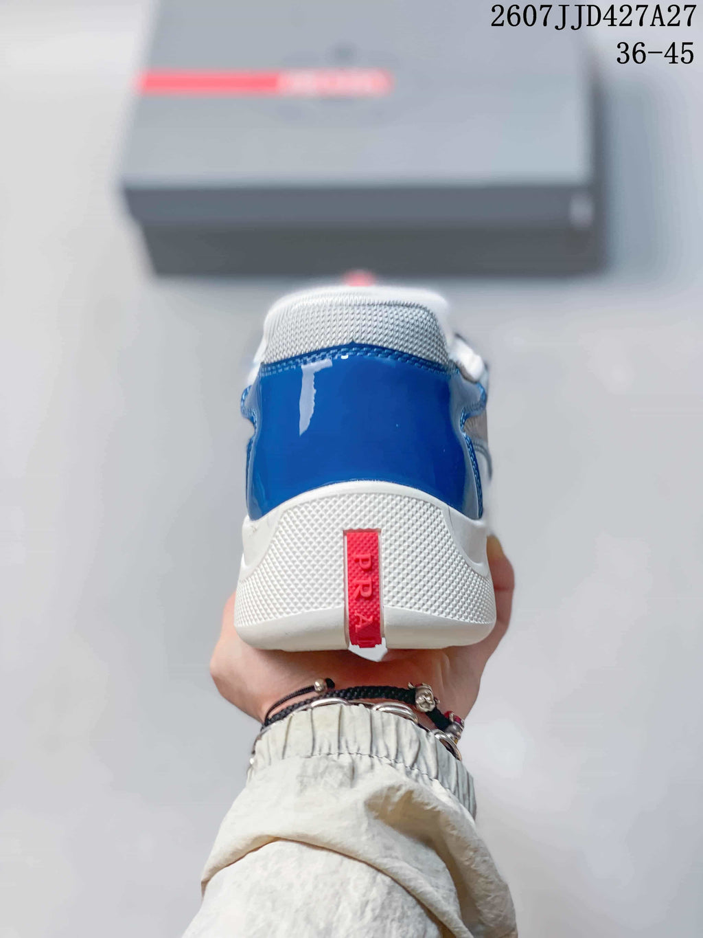 Rear view of the blue sneaker showing the white heel section and red Prada strap.