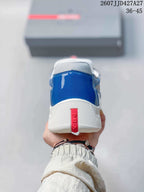 Rear view of the blue sneaker showing the white heel section and red Prada strap.