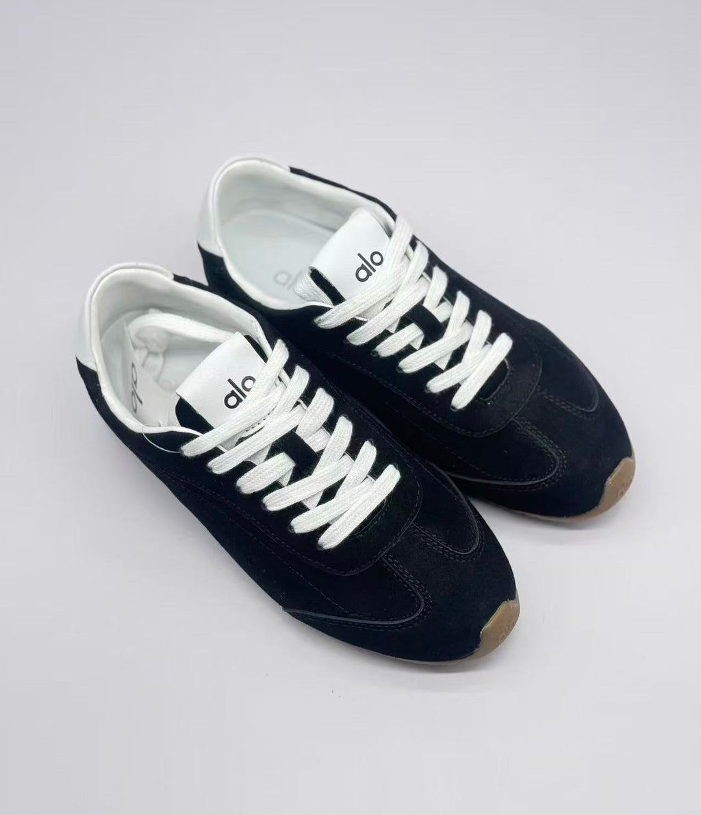 Top three-quarter view showing the pair's black uppers, white laces, and Alo tongue branding.