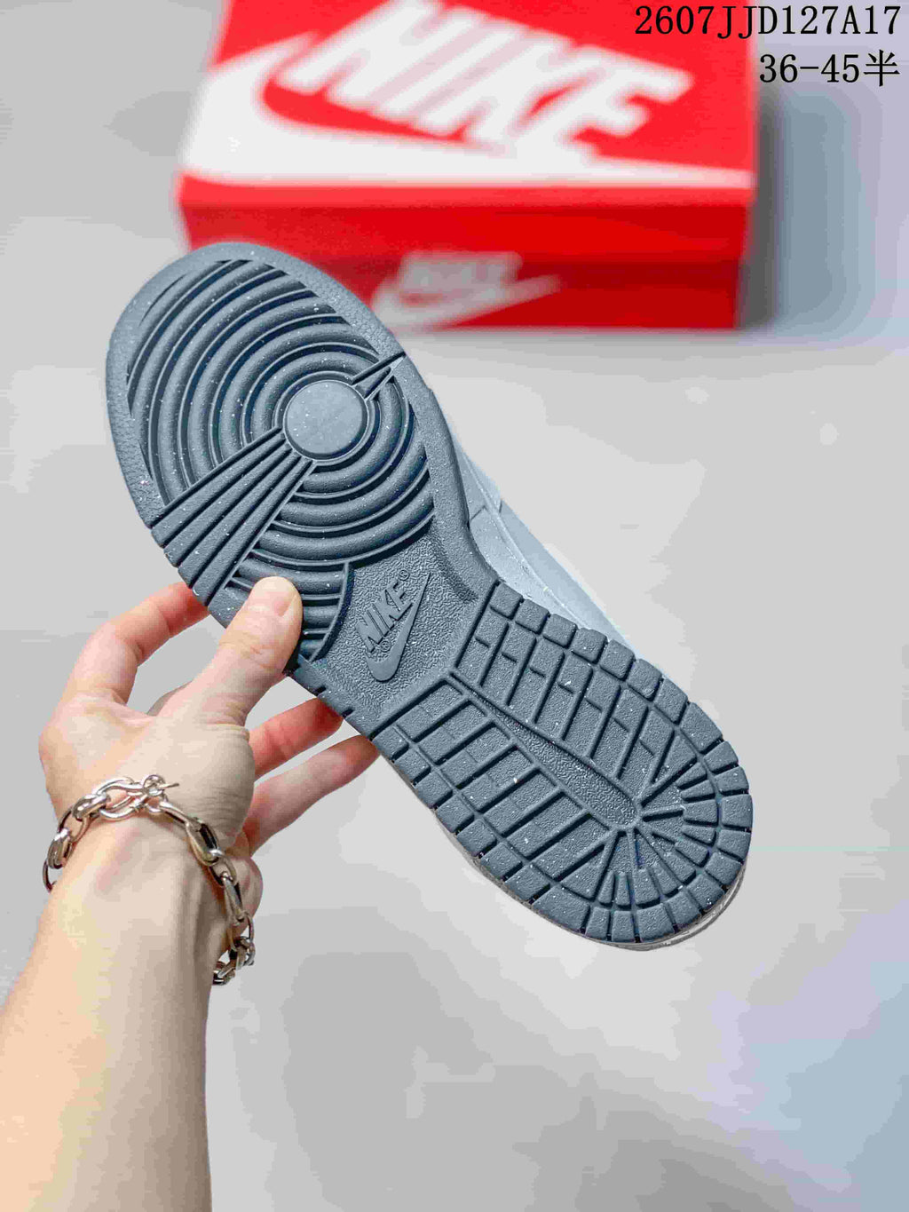 Underside view of the sneaker showing the dark textured rubber outsole and circular traction pattern.