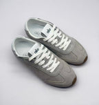 Top three-quarter view showing the gray uppers, white laces, tongue branding, and insoles.