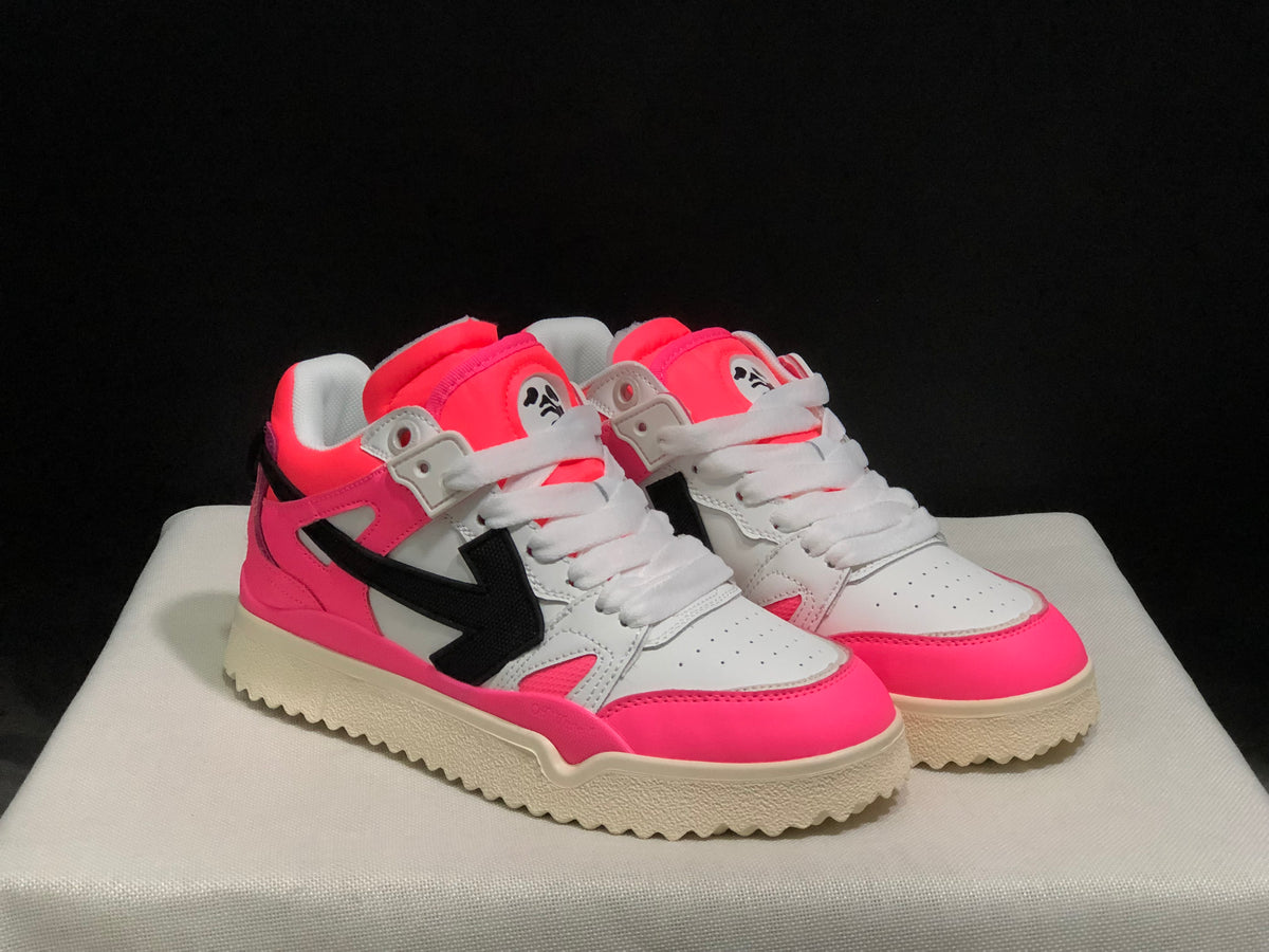 Front three-quarter view of the pair highlighting the pink toe overlays, white uppers, black side arrows, and cream outsoles.