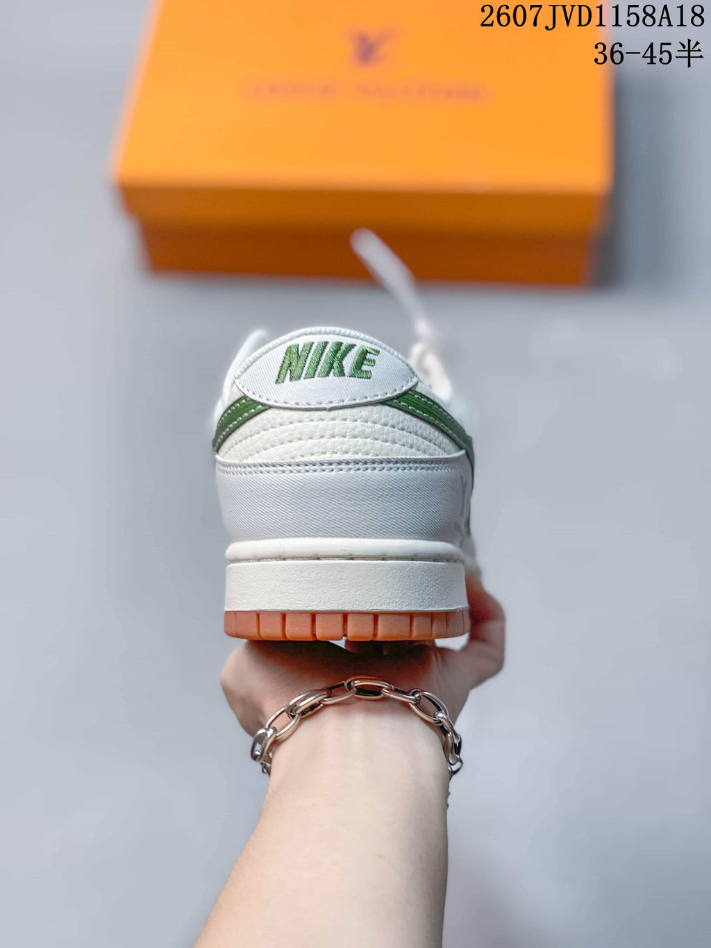 Rear view of a sneaker showing a white heel, green detailing, gum outsole edge, and Nike branding on the tongue.