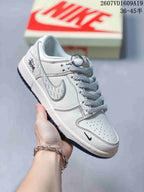 Close-up of a white Nike Dunk Low sneaker with light patterned laces, perforated toe box and decorative side details.