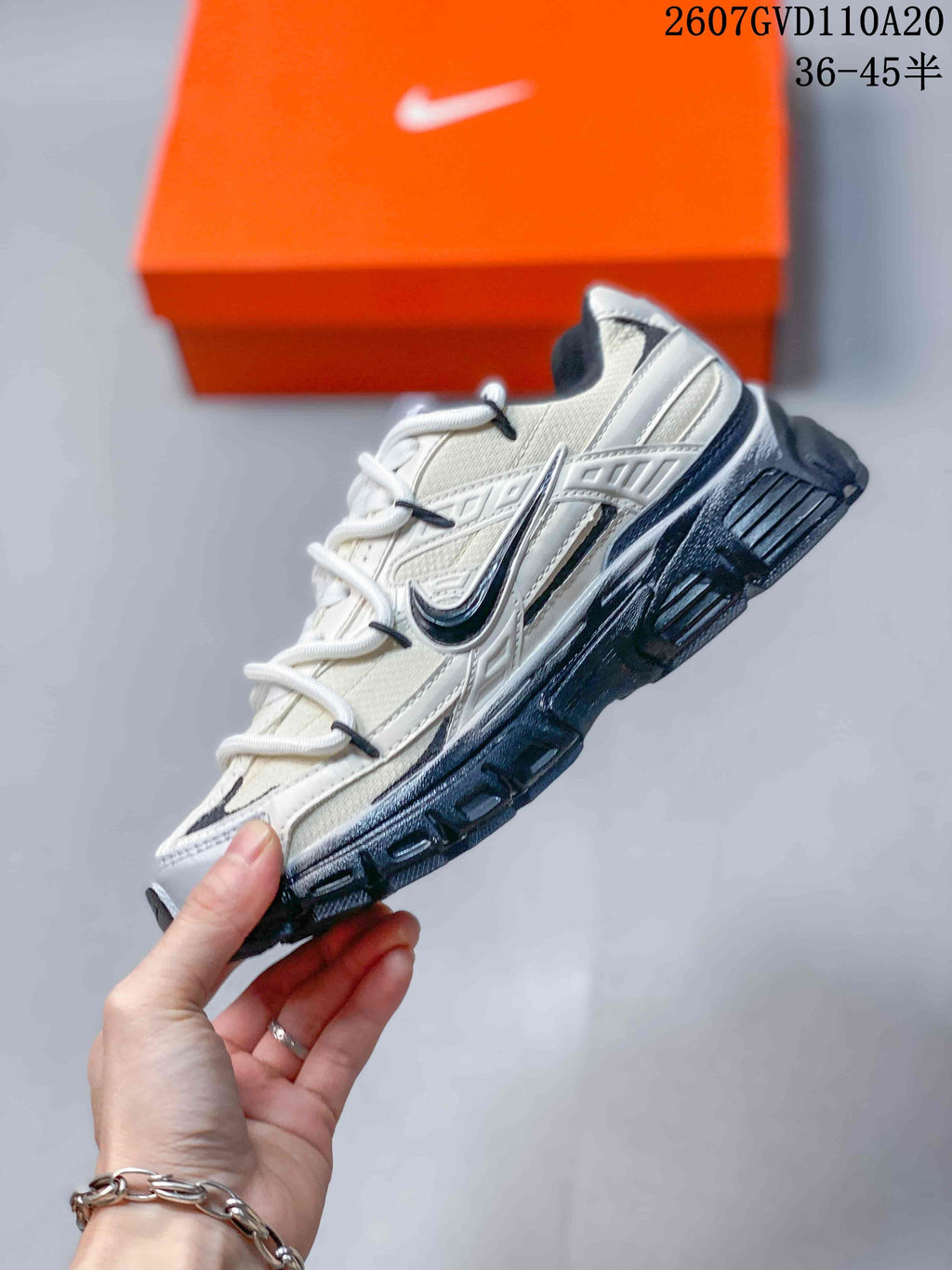 Side view of the grey and white low-top sneaker showing layered upper panels, contrast Swoosh detailing, laces, and the dark outsole.