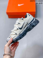 Side view of the grey and white low-top sneaker showing layered upper panels, contrast Swoosh detailing, laces, and the dark outsole.