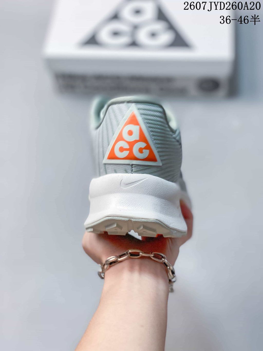Rear view of a Nike ACG sneaker showing the orange ACG heel logo, padded collar, white heel section, and outsole edge.