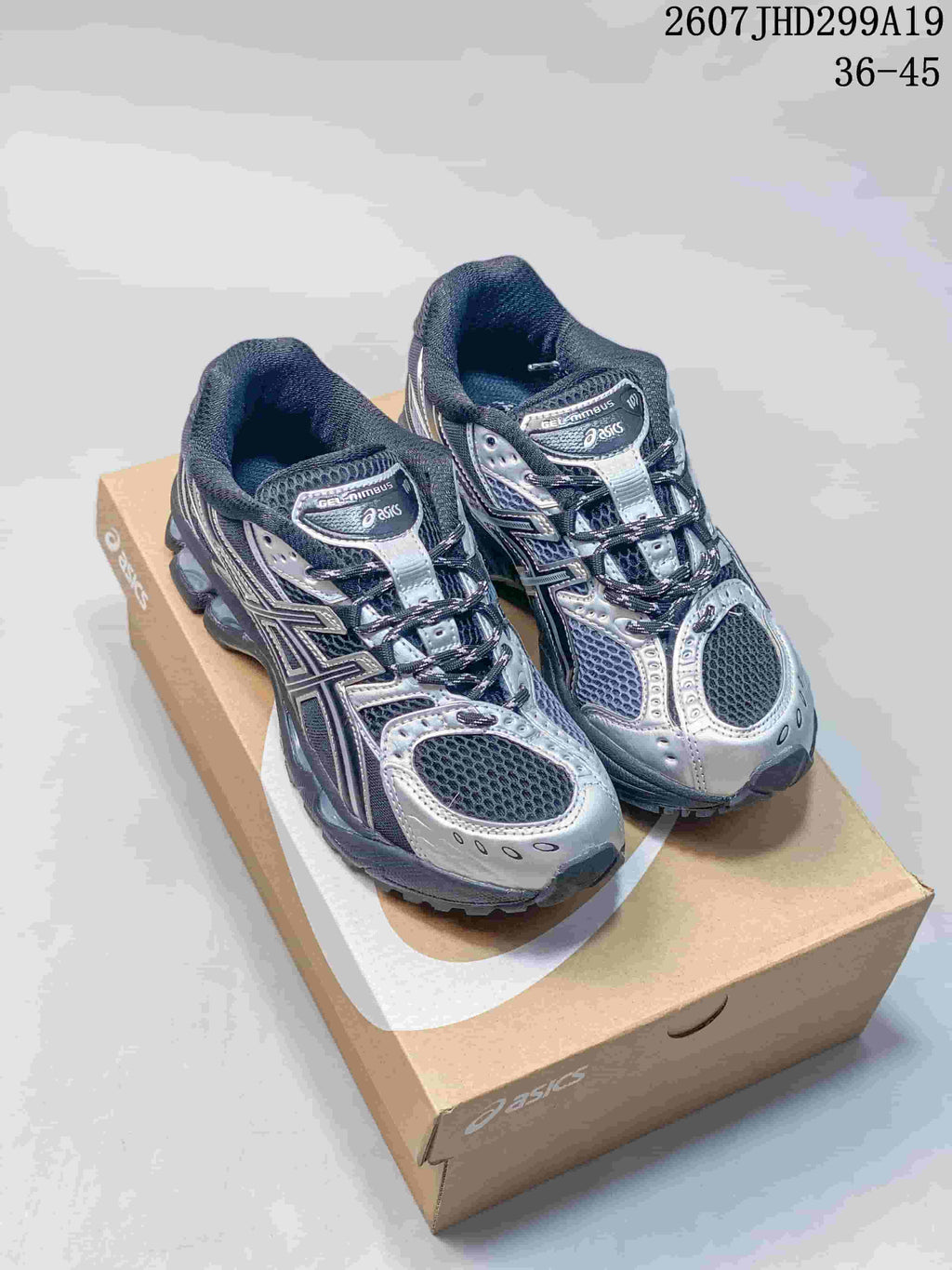 Pair of black and silver ASICS Gel-Nimbus 10.1 sneakers displayed on an ASICS shoebox; image text shows style code 2607JHD299A19 and size range 36–45.