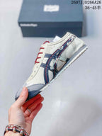 Side profile of the sneaker showing the navy Onitsuka Tiger stripes, red stitching, cream upper, and gray toe panel.