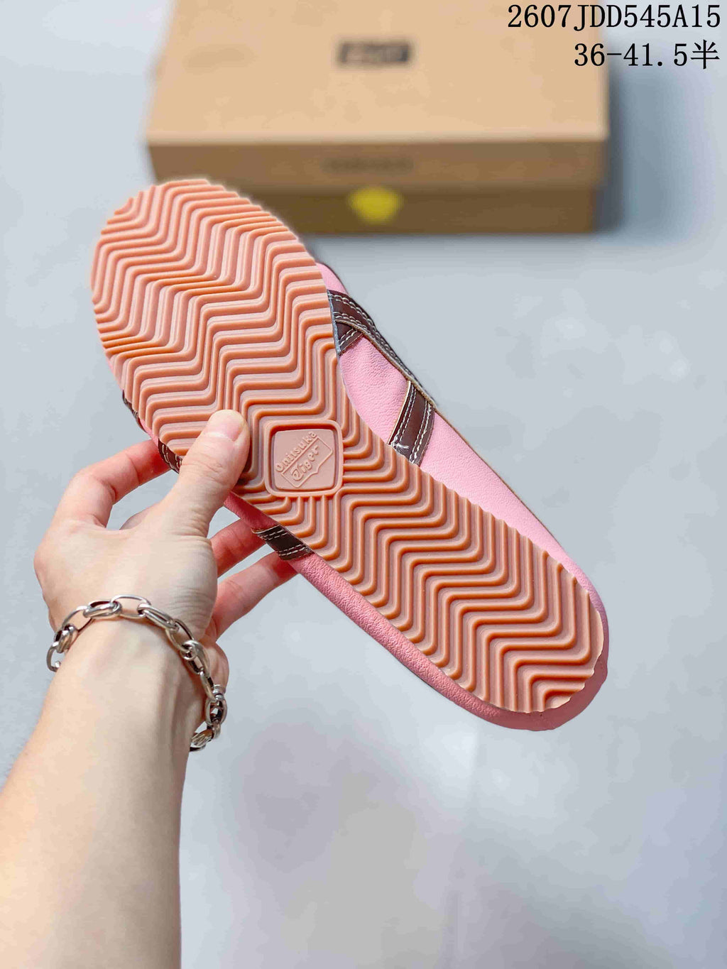 Close-up of the sneaker outsole showing a pink zigzag tread pattern and central embossed branding.
