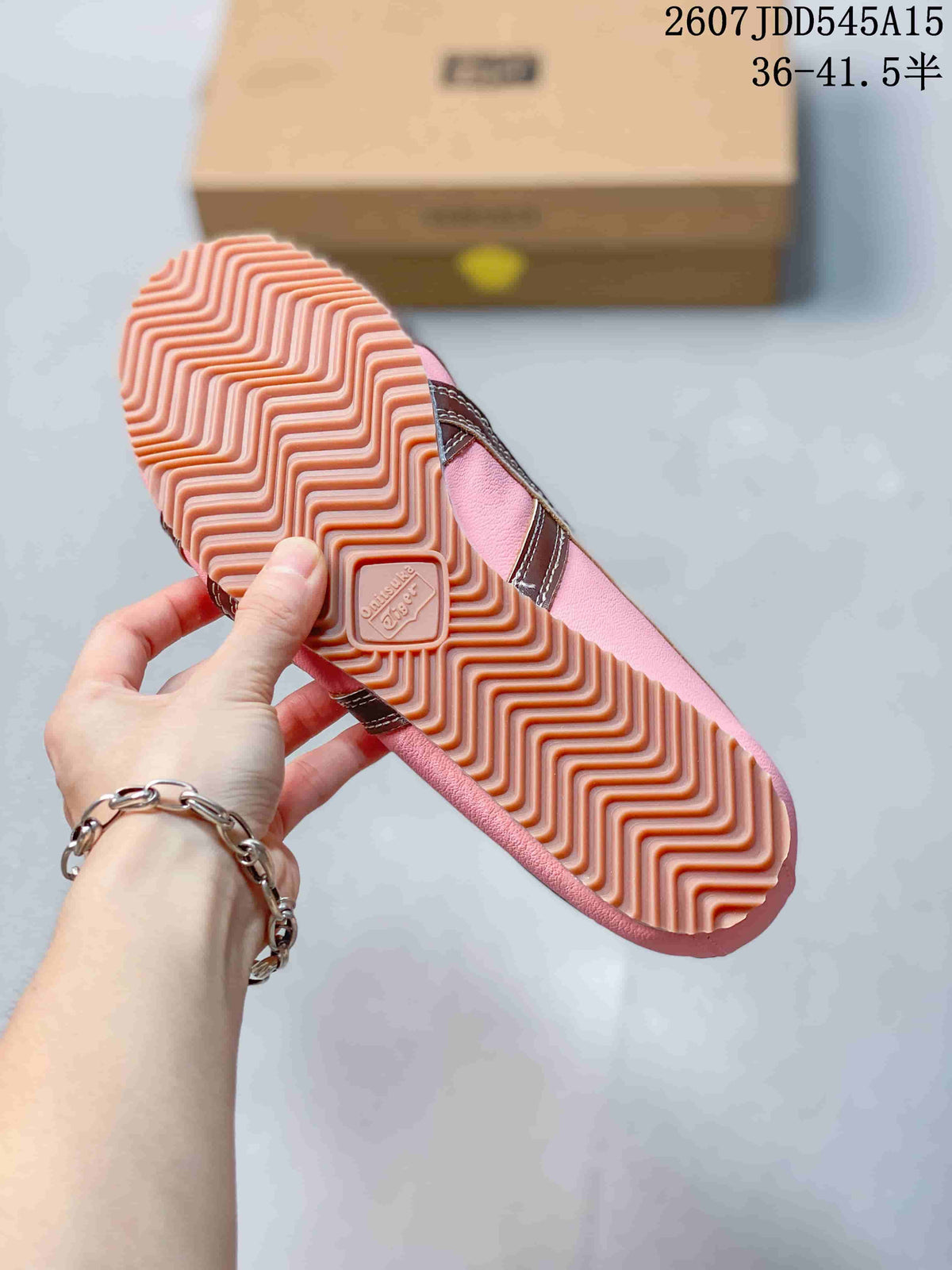 Close-up of the sneaker outsole showing a pink zigzag tread pattern and central embossed branding.