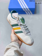 Angled side view highlighting the white upper, green and yellow stripes, lace panel and gum outsole.