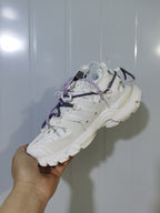 Side and underside view of the white Balenciaga sneaker, showing the panel construction, heel shape, and textured outsole.