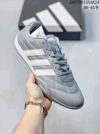 Gray and white adidas Adipista low-top sneaker shown at an angle with gray laces and three white side stripes.