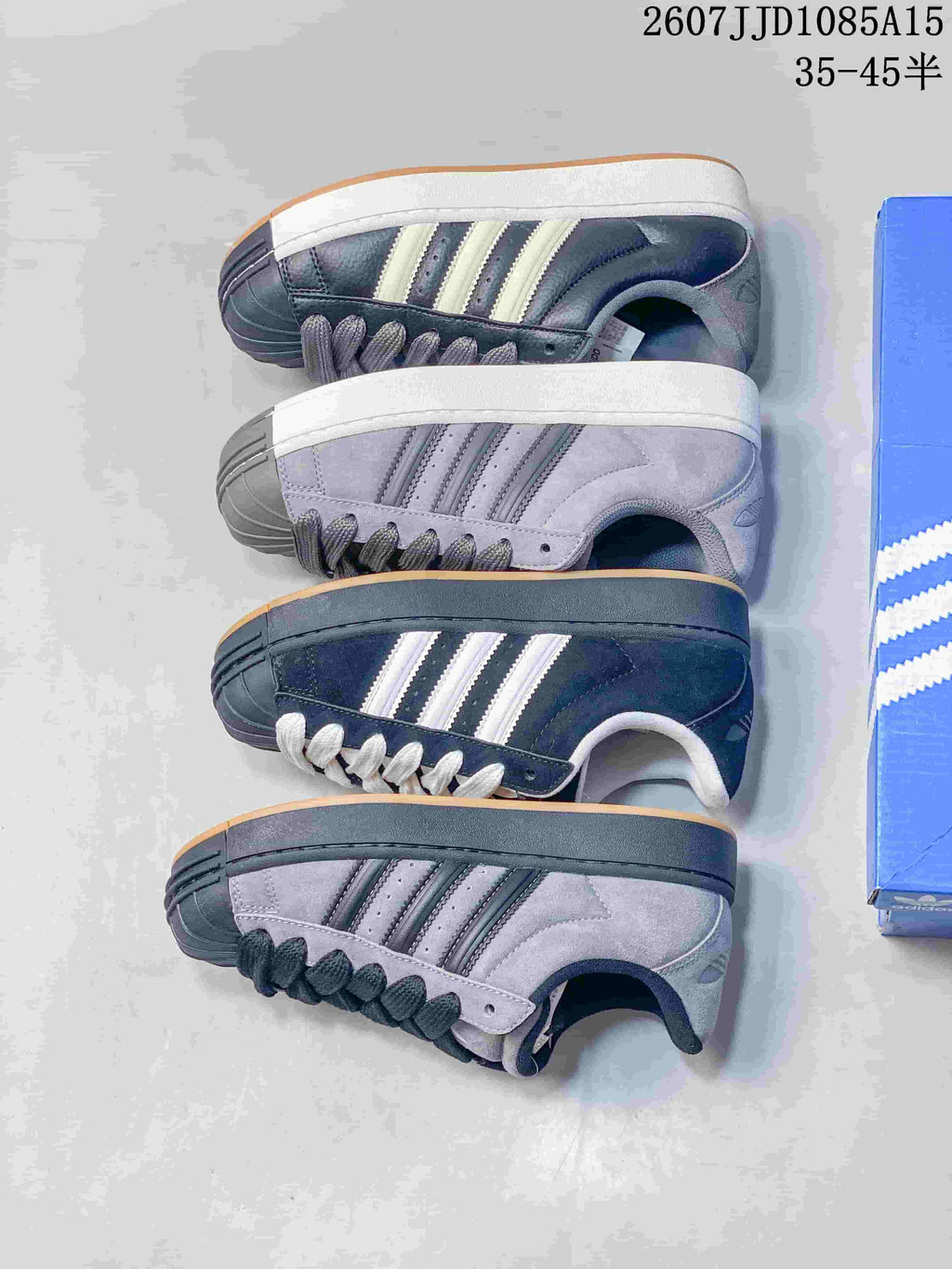 Several black and gray adidas shell-toe sneakers arranged together to show different colorways.