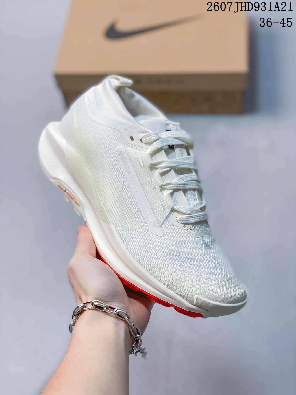 Angled side view of the white sneaker showing the textured upper, side Swoosh, ReactX branding, and red outsole accent.
