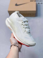 Angled side view of the white sneaker showing the textured upper, side Swoosh, ReactX branding, and red outsole accent.