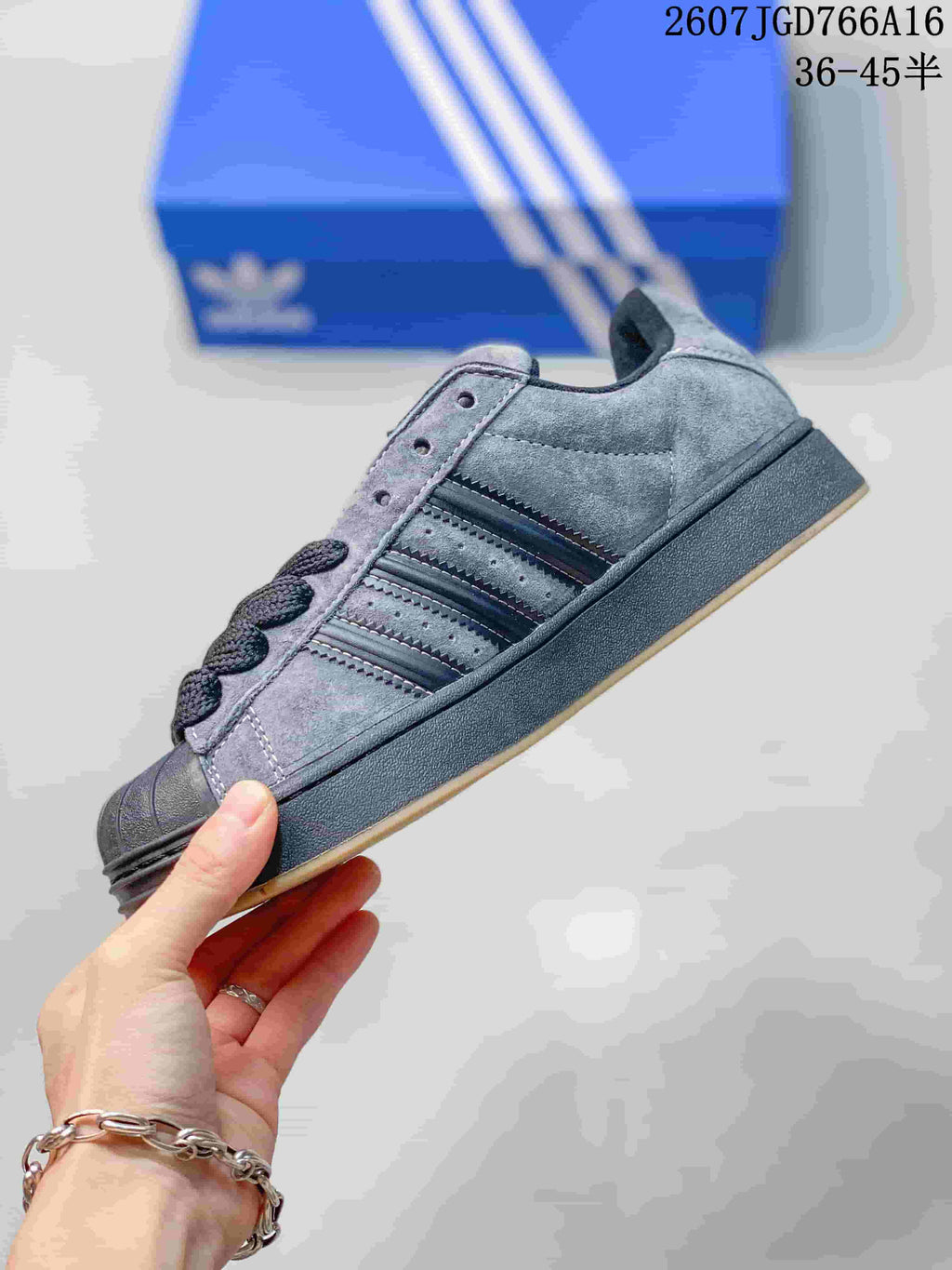 Side view highlighting the grey upper, black three-stripe detailing and gum outsole.