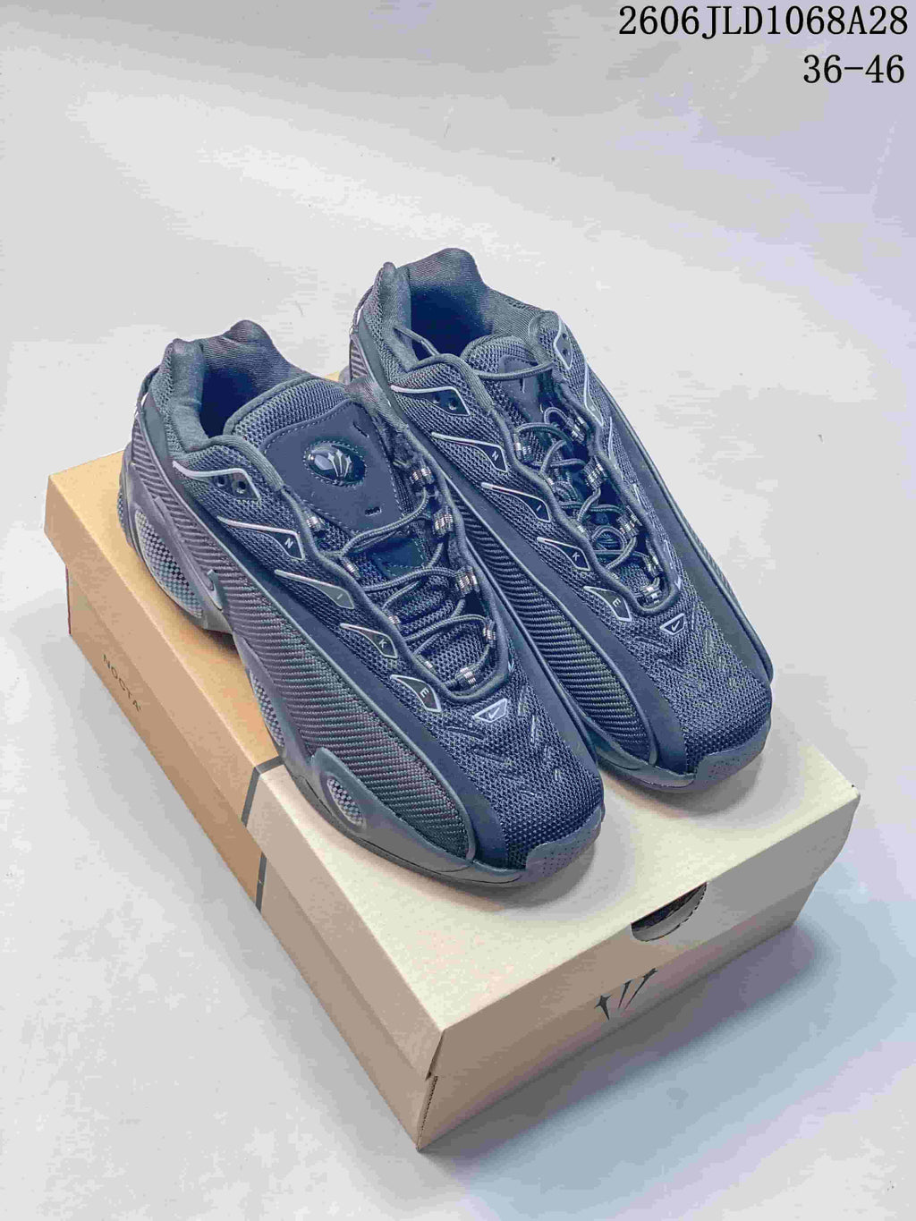 Pair of dark Nike NOCTA Glide low-top sneakers shown from above on a box.