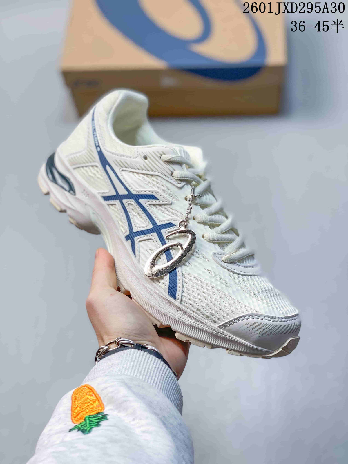 Light-colored ASICS GEL-KAHANA 8 trail shoe with blue accents and a hanging logo charm.