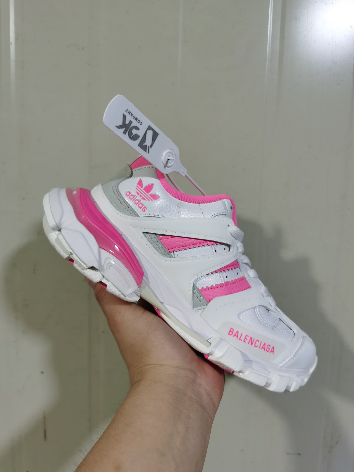 Angled front view showing Adidas branding, pink accents, grey panels, and Balenciaga text on the toe area.
