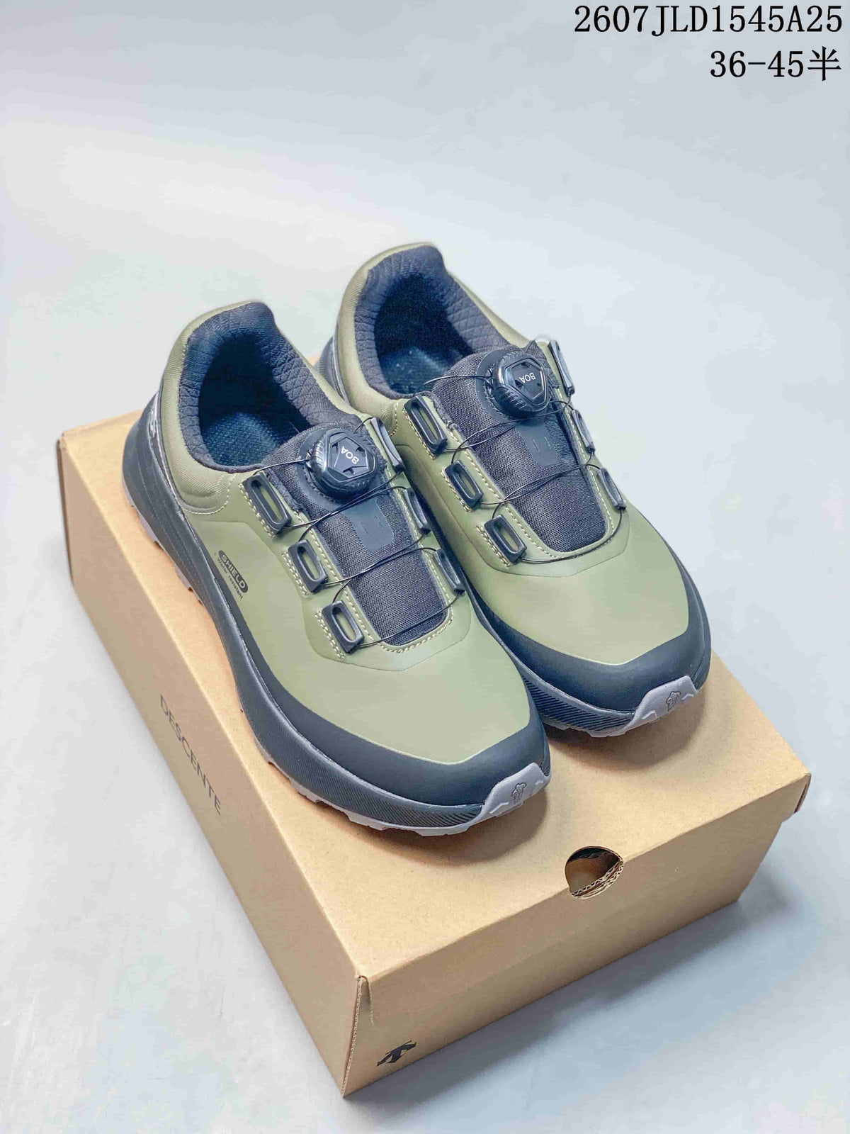 Pair of olive and black Descente low-top sneakers displayed on a shoebox, showing the quick-lacing dials and padded collars.