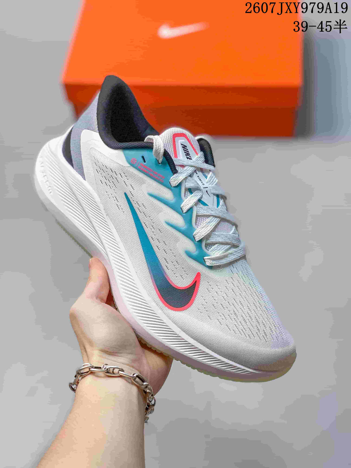 White Nike running sneaker with turquoise and pink accents and a light-colored outsole.
