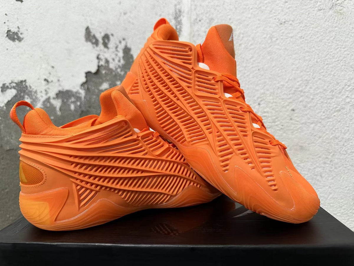 Orange Adidas basketball sneakers displayed at an angle, showing their cage-style sides and sculpted soles.
